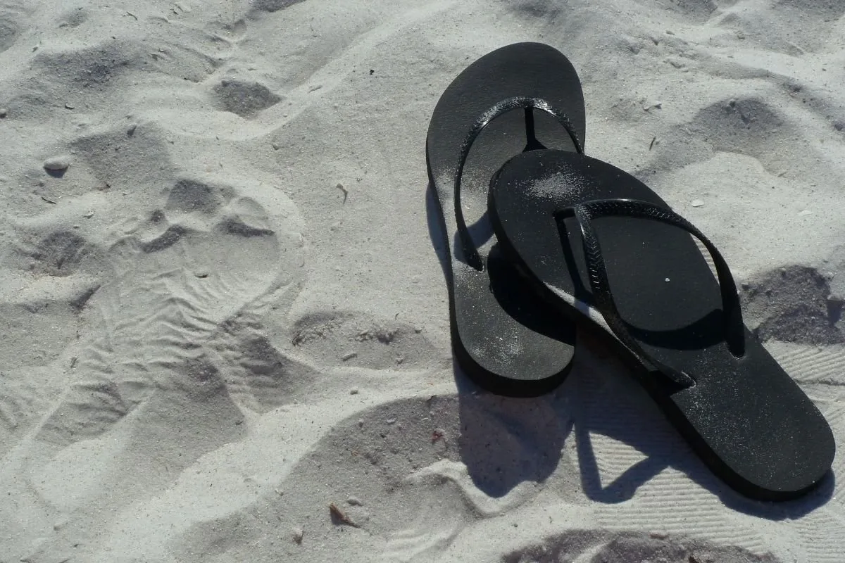 A black flip-flop on a sand.