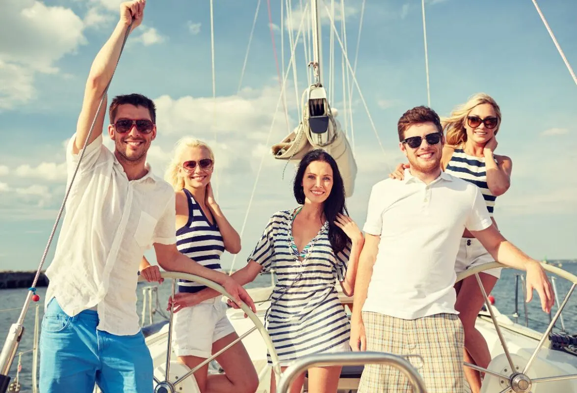 A group of friends in the yacht smiling in the camera.