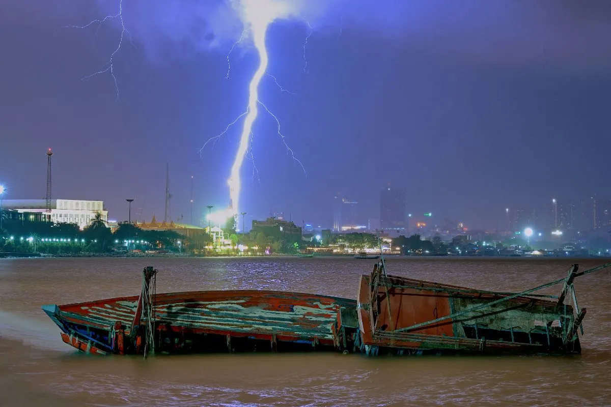 A boat drowning in the sea with a lightning strike.