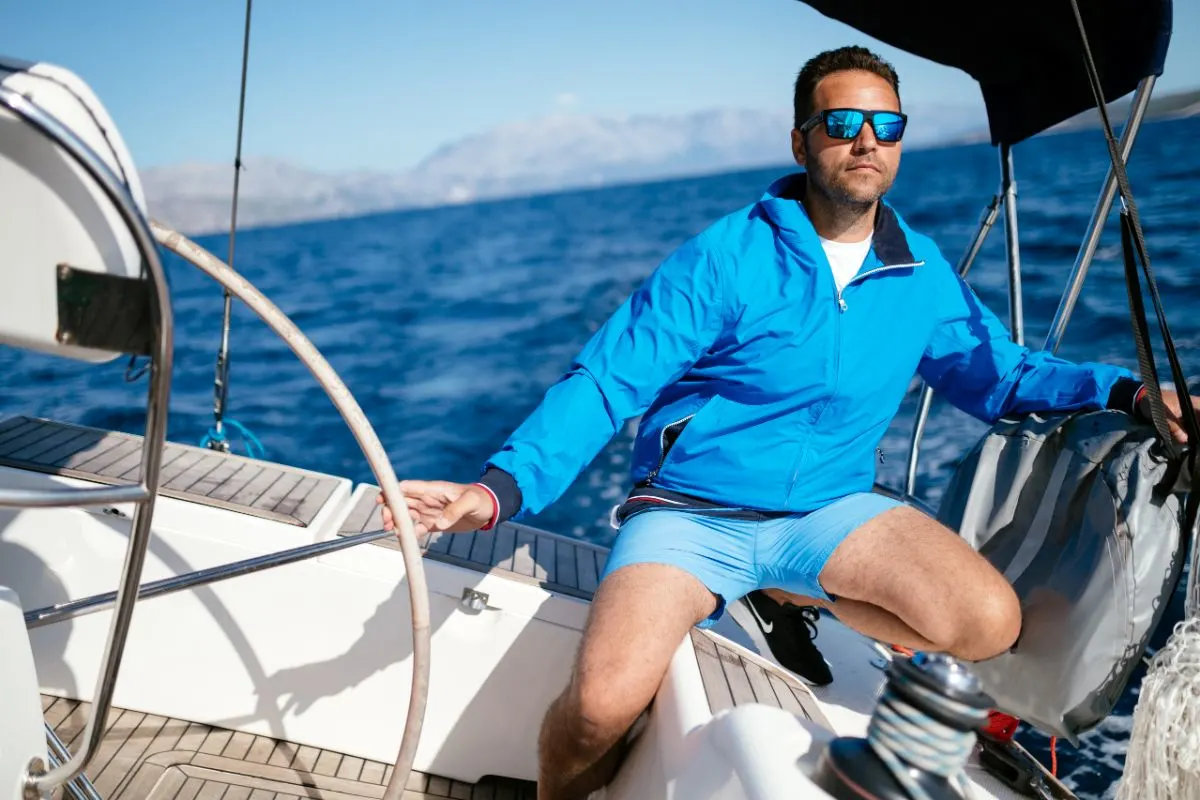 A man in a blue outfit riding in his yacht.