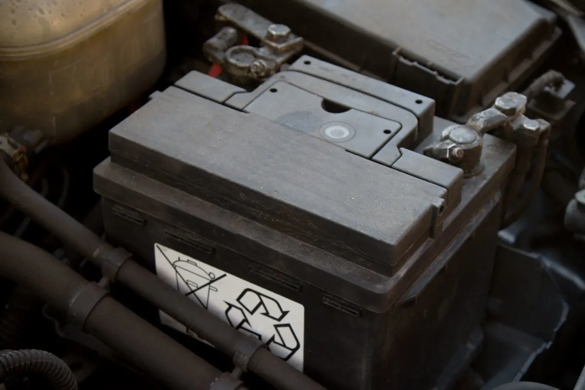 Black battery in isolation placed in an engine bay.