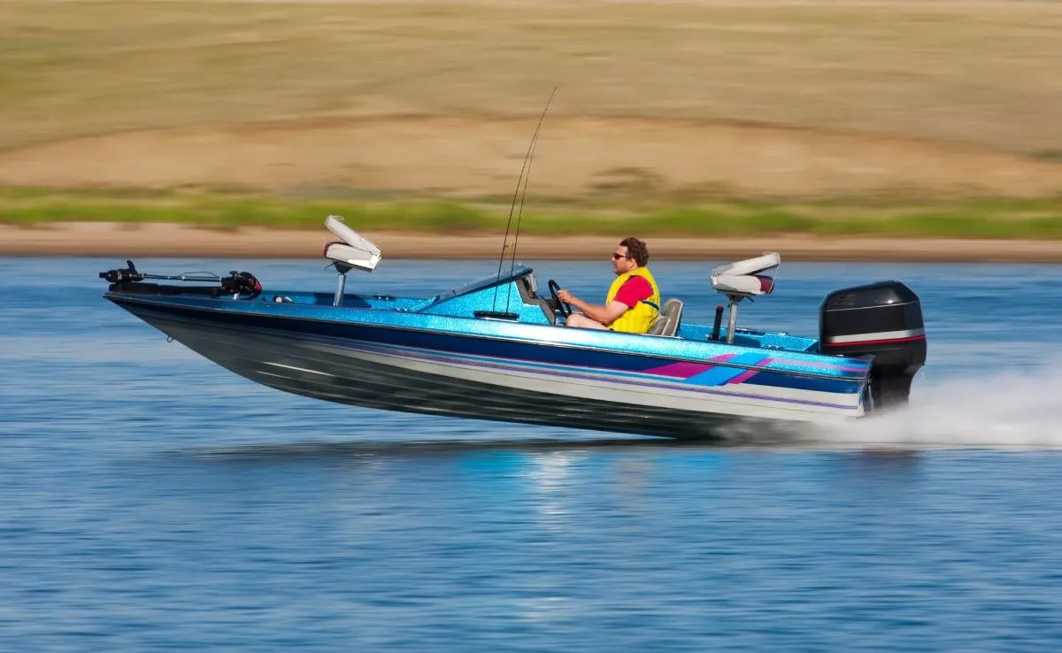 A man driving a outboard boat motor so fast.