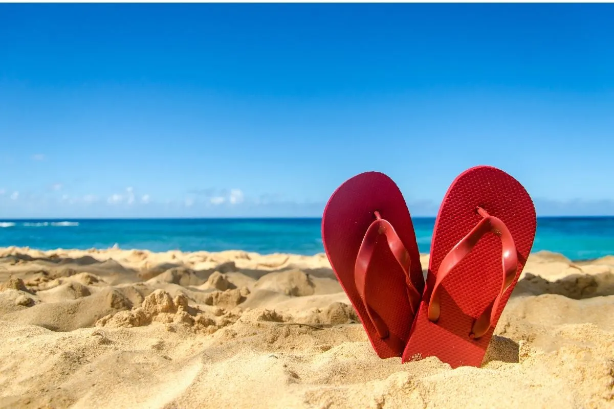 A pair of red flip-flop on the shore.