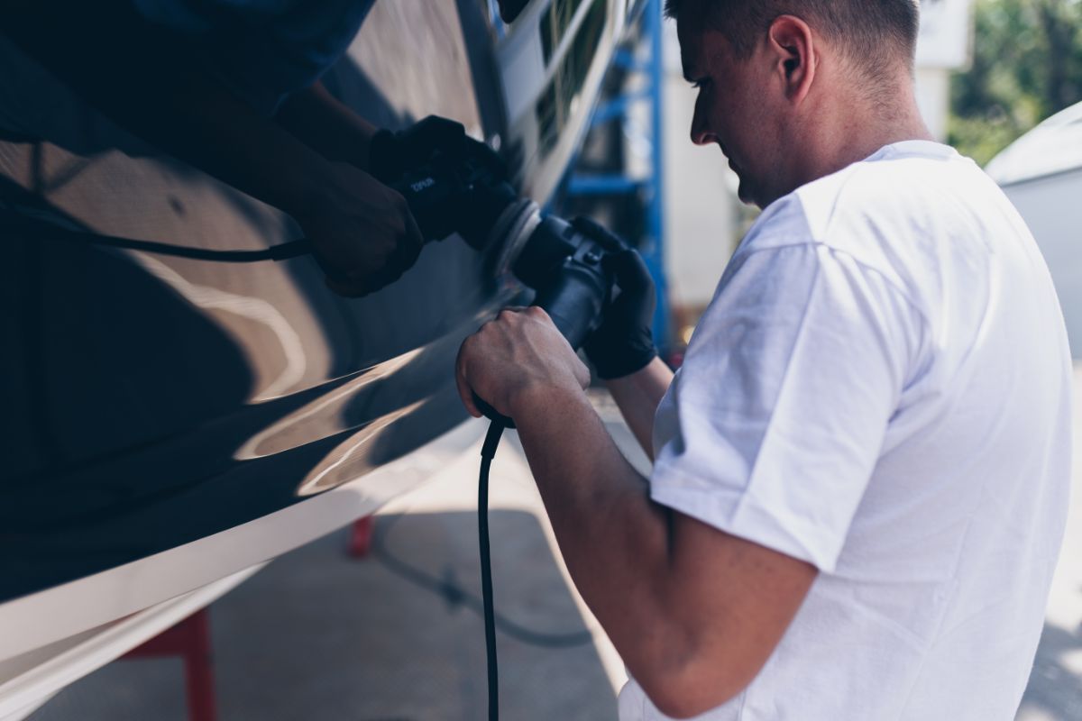 A man in a white shirt repairing the boat.