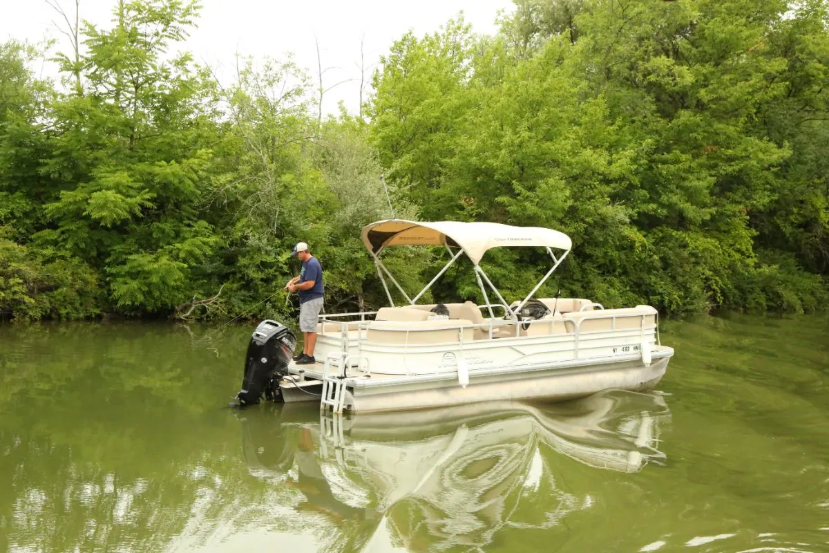 A fisherman on pontoon boat fishing in the lake.