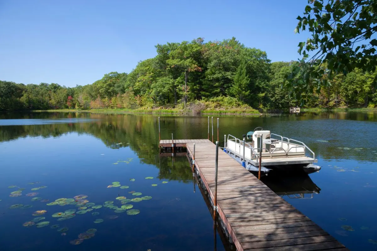 A pontoon boat on a sunny clear day with a dock.