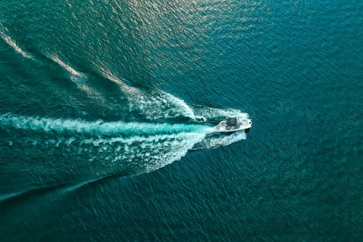 A boat speeding up making bubbles in the lake aerial view.