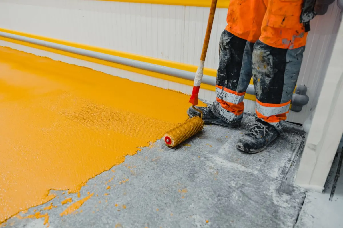 A worker applying a polyurethane floor system paint.