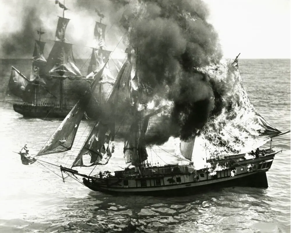 Wooden boat on fire on the sea.