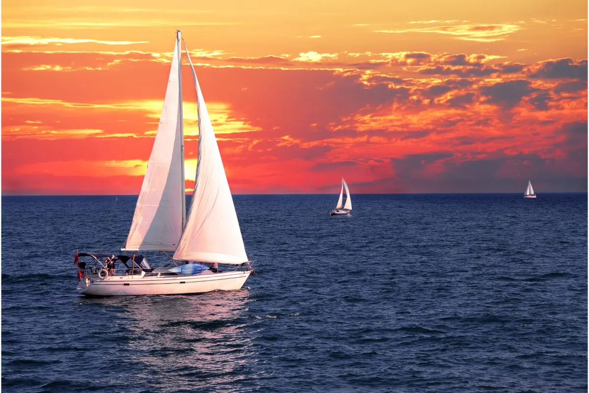 A photo of a boat sailing on a calm evening with beautiful sunset background.