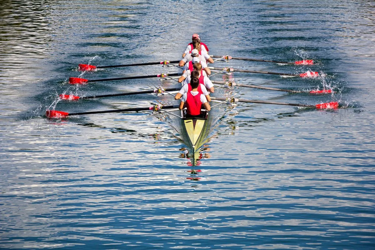 Back view of eight men rowing on the river.