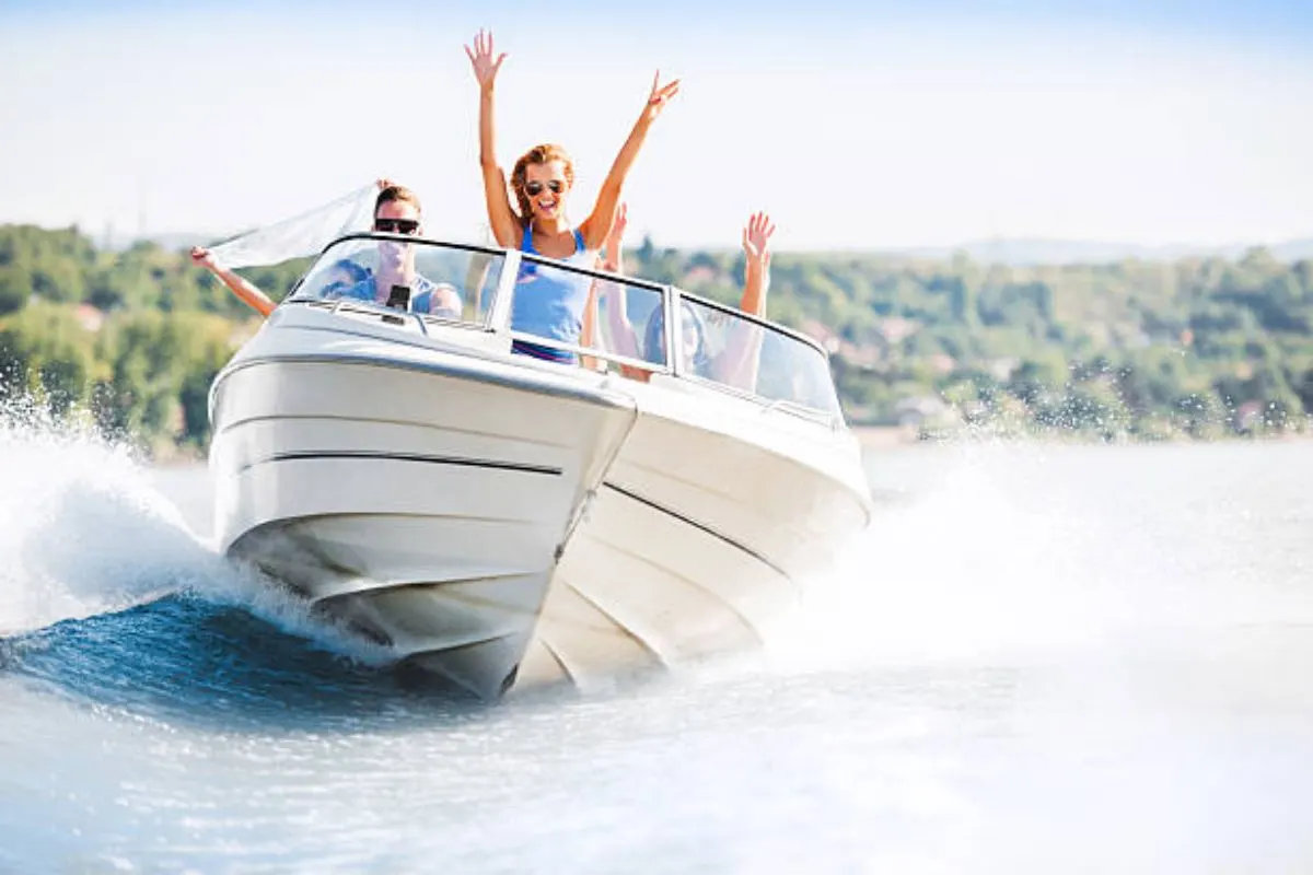 Cheerful young woman having fun while riding their motor boat on the sea during vacation.