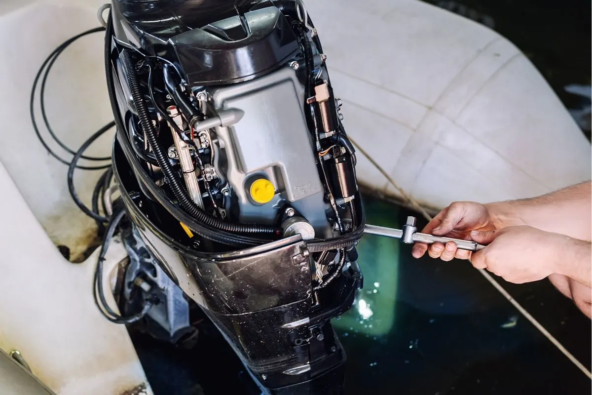 A boat mechanic doing maintenance repair to an engine of a motor boat at his boat garage.