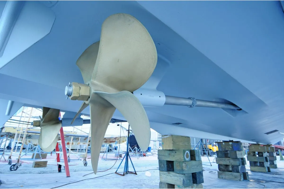 A five-bladed boat propeller in white under the blue boat.