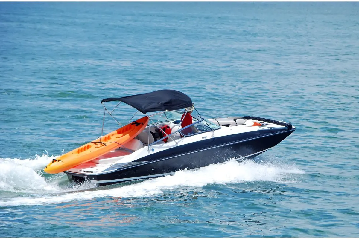 Man driving a motor boat carrying an air inflated boat in the seas of Italy.