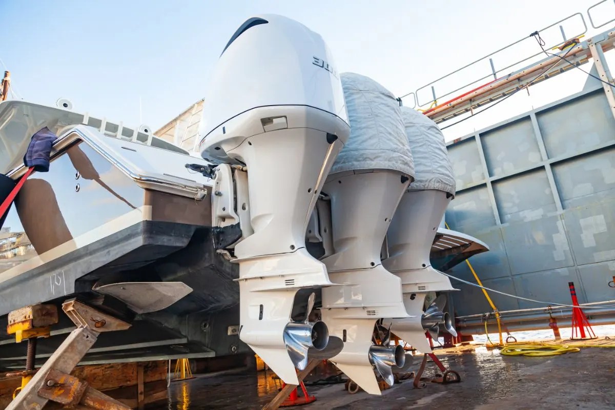 Three outboard motors mounted on a transom mount at the stern of the boat in dry dock.