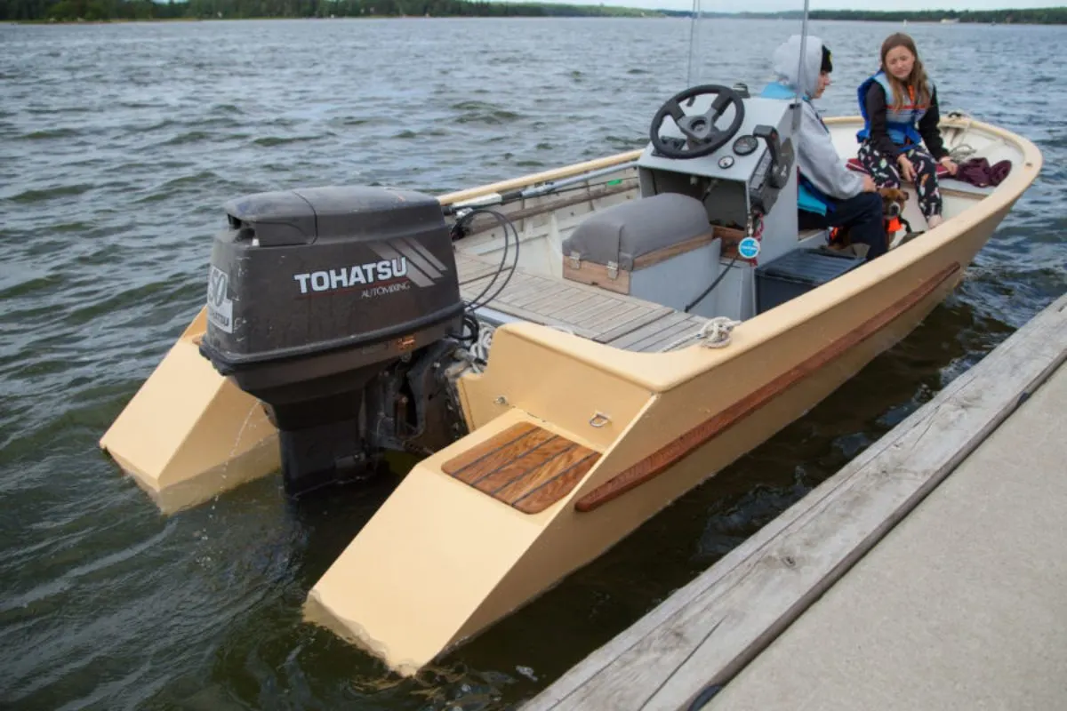 A small motor boat with reversed transom parked at the docks with man and a woman talking.