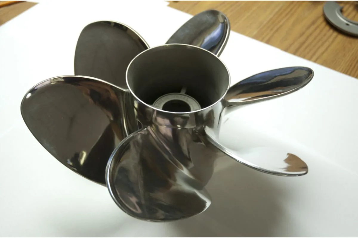 A six-bladed boat propeller in silver on a white table background.