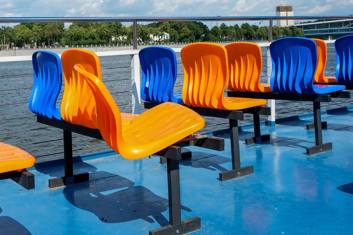 Orange and blue colored vacant bleacher seats on a passenger boat. 