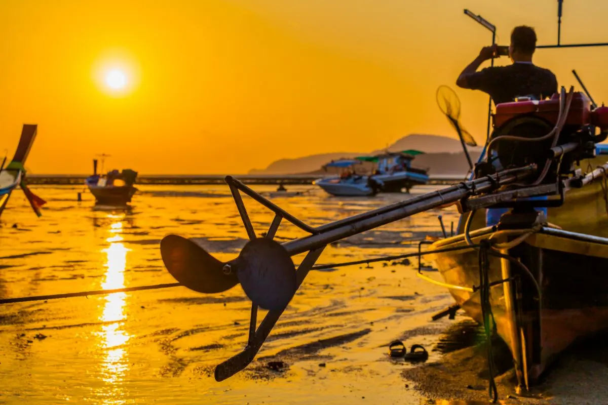 Two blade of boat propeller attached in a boat with a man sightseeing the sunset background.