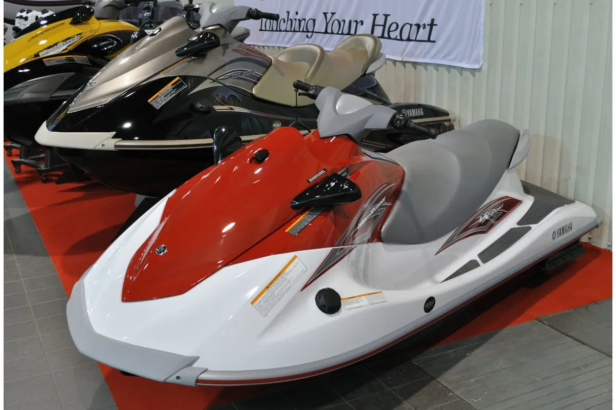 Three different colors of jetski are arranged for sale.