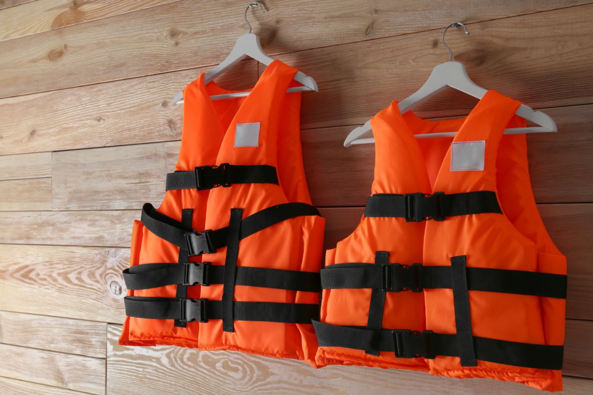 Orange life jacket hanged against the wooden background.