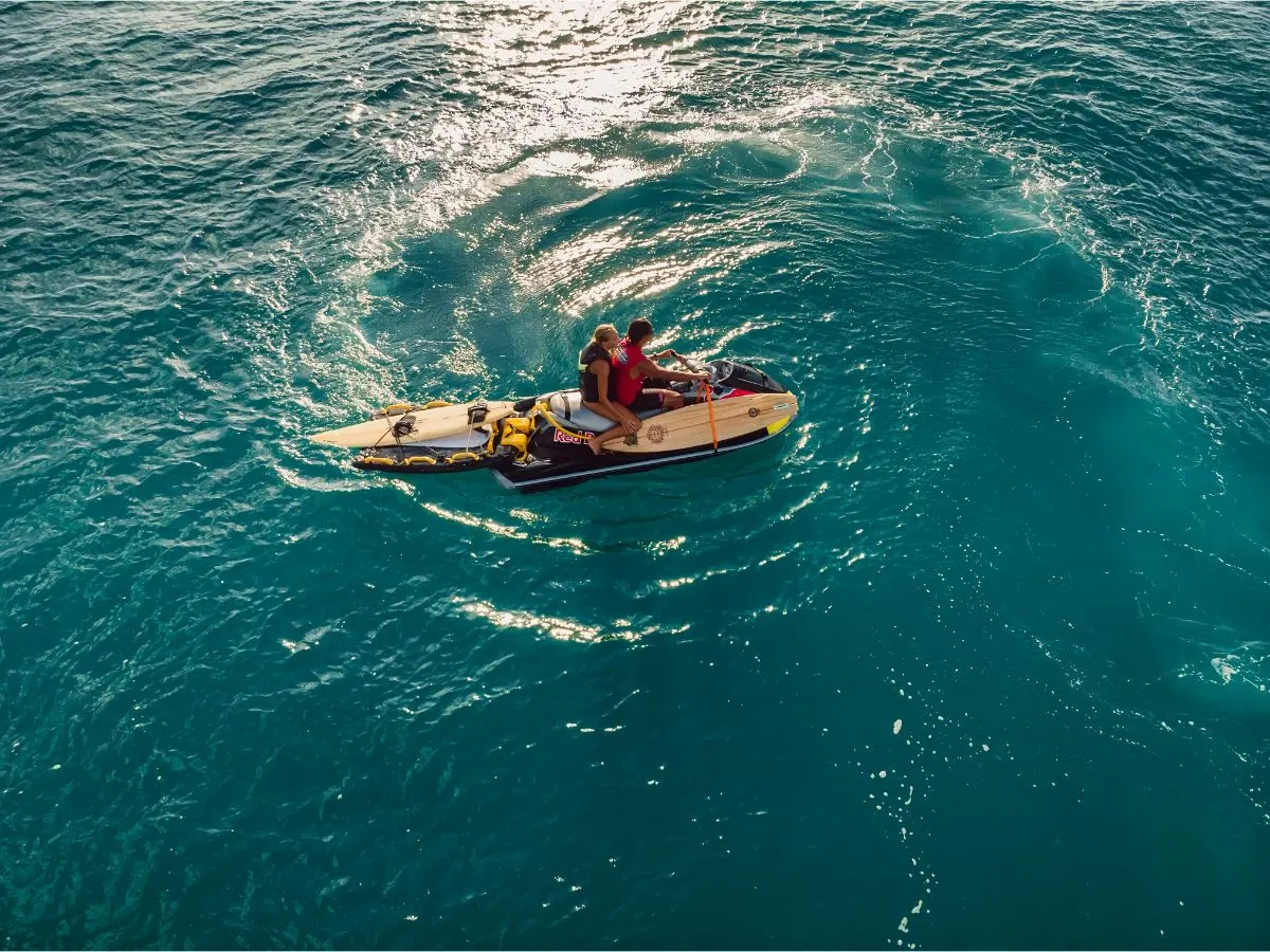 Top view of two man on a jestki towing a surf board.